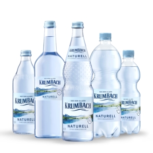 Fünf Krumbach Naturell Flaschen aus Glas und PET in verschiedenen Größen ohne Kohlensäure nebeneinander