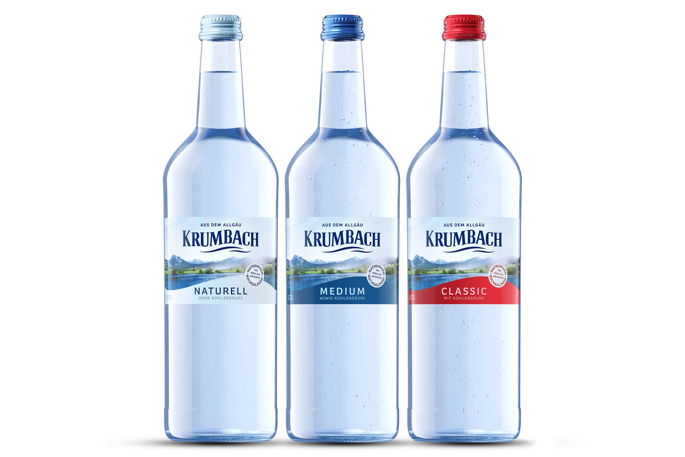 Drei 0,75L-Glasflaschen Krumbach Mineralwasser: Naturell, Medium, Classic. Farbige Schraubverschlüsse, weißer Hintergrund.