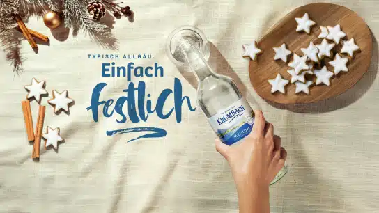 Krumbach Mineralwasser Flasche in festlichem Ambiente mit Lebkuchensternen und Zimtstangen, unter dem Schriftzug "Einfach festlich