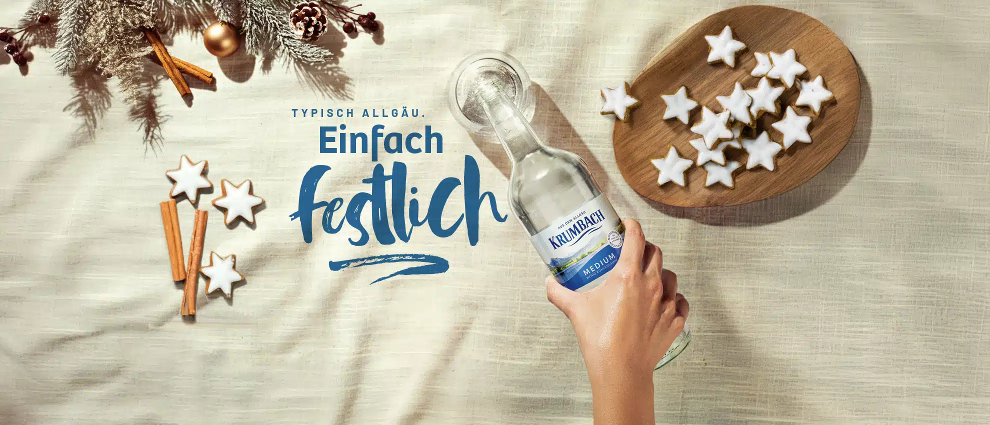 Krumbach Mineralwasser Flasche in festlichem Ambiente mit Lebkuchensternen und Zimtstangen, unter dem Schriftzug 