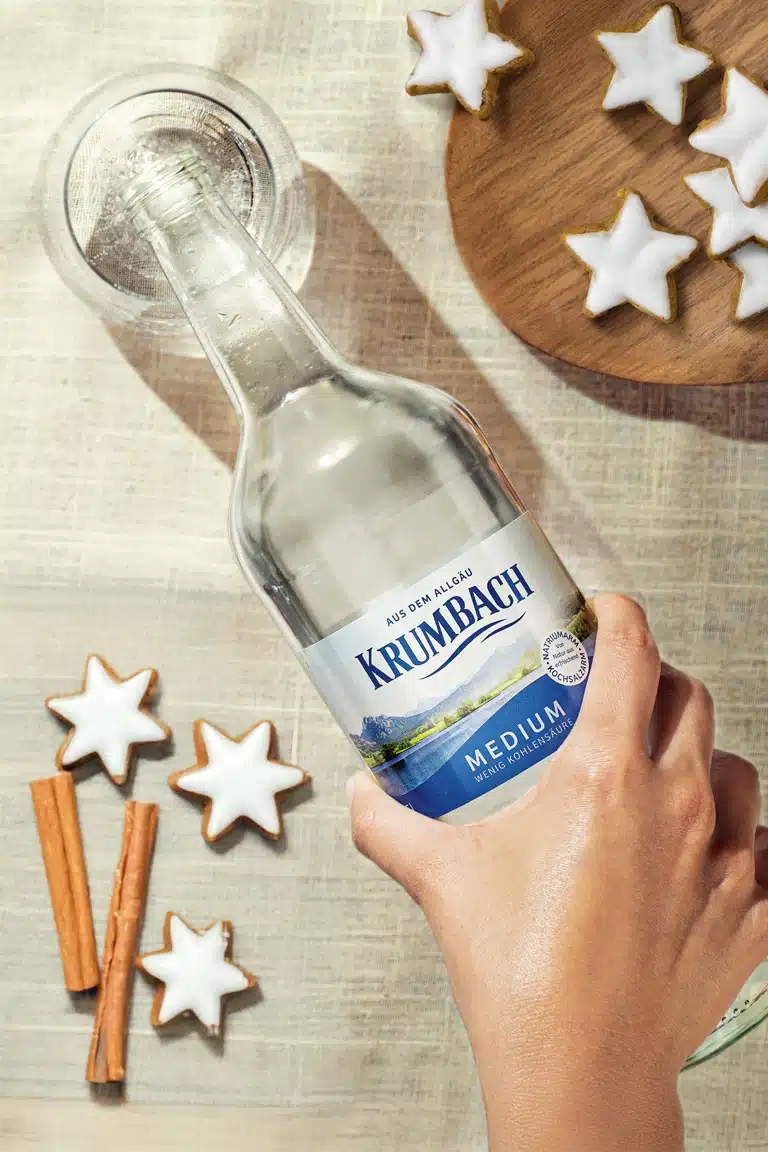 Krumbach Mineralwasser Flasche in festlichem Ambiente, umgeben von Zimtstangen und Lebkuchensternen