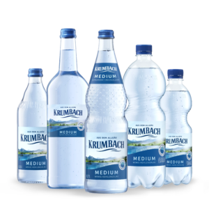 Fünf Krumbach Medium Flaschen mit wenig Kohlensäure in Glas und PET, nebeneinander auf weißem Hintergrund