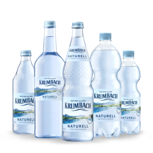 Fünf Krumbach Naturell Flaschen aus Glas und PET in verschiedenen Größen ohne Kohlensäure nebeneinander