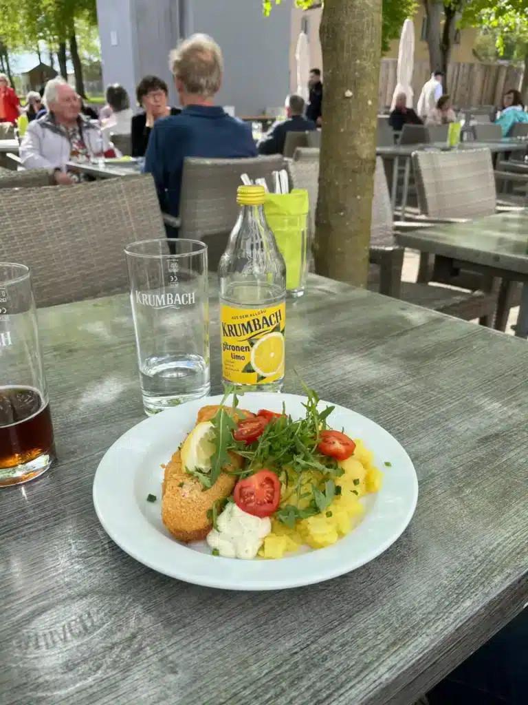 Krumbach Zitronenlimo neben einem Teller mit Essen auf einer Terrasse der Landesgartenschau Wangen