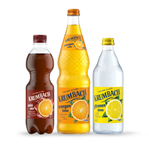 Flaschen aus dem Krumbach Limonaden Sortiment in verschiedenen Gebinden und in den Sorten Orange, Zitrone und Cola-Mix