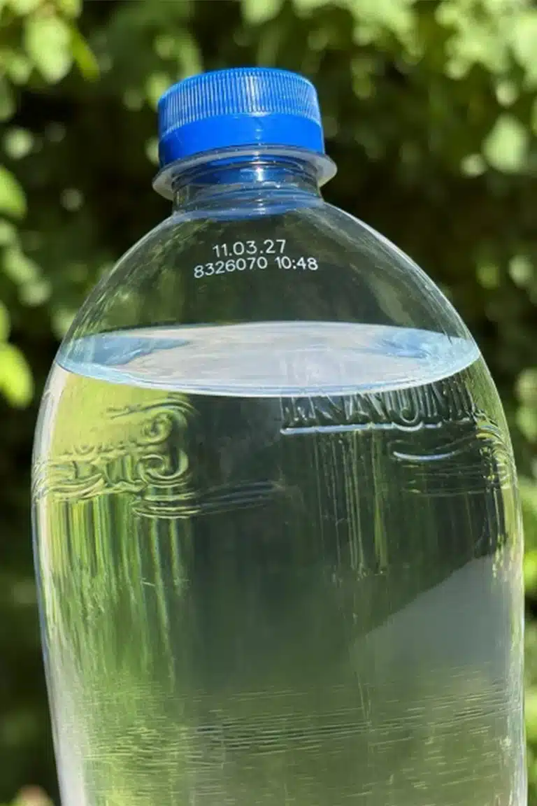 Krumbach PET-Flasche mit Mineralwasser und blauem Verschluss vor grüner Naturkulisse