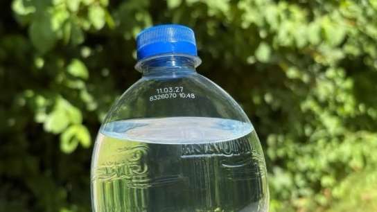 Krumbach PET-Flasche mit Mineralwasser und blauem Verschluss vor grüner Naturkulisse