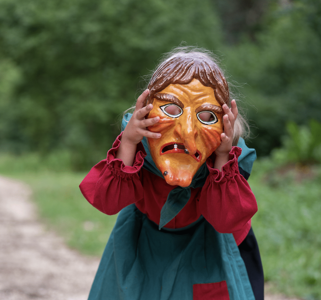Kind mit Hexenmaske im Wald