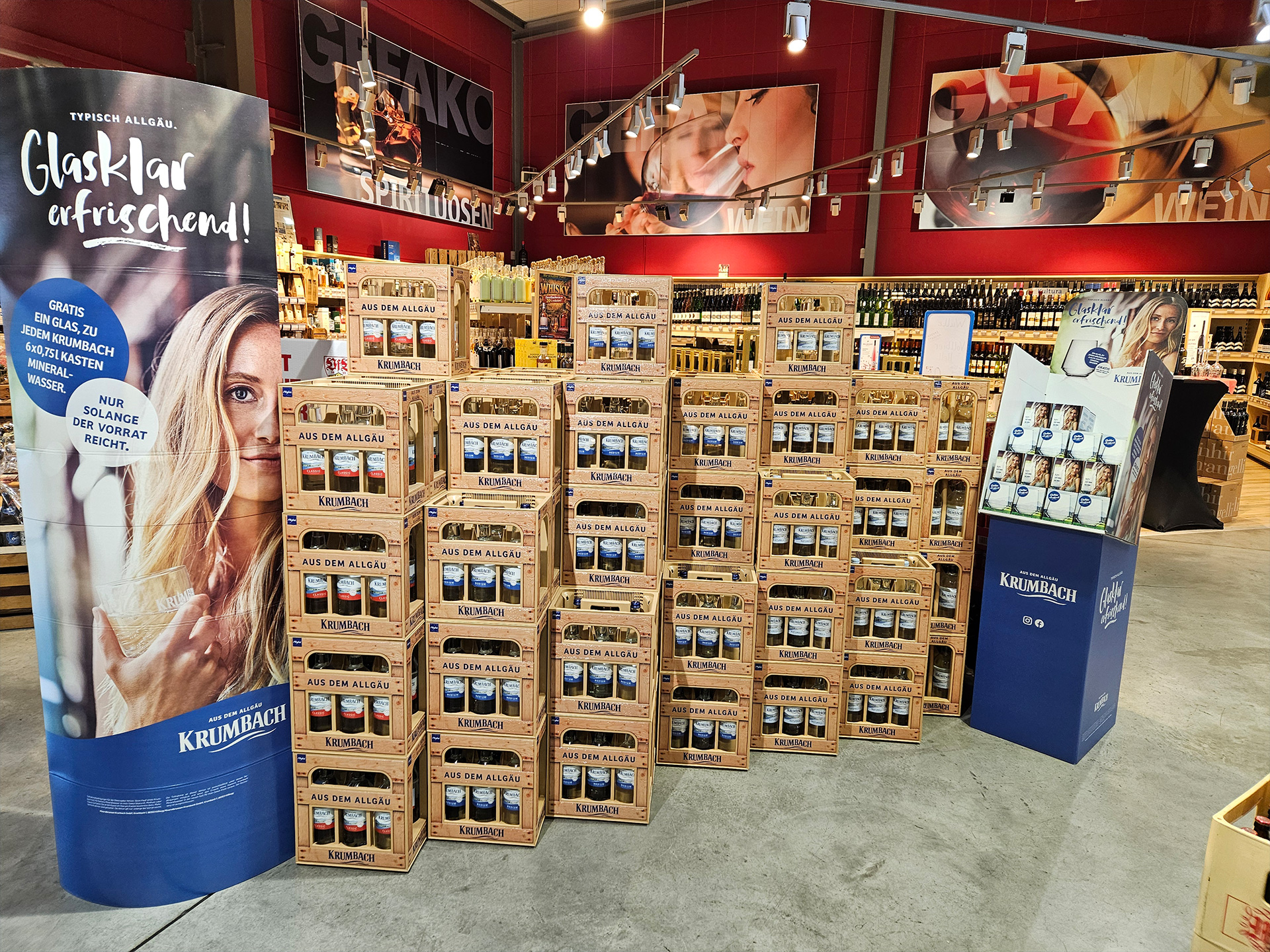 Krumbach Mineralwasser in den Sorten Naturell, Medium und Classic in Holz-Mehrwegkisten mit Aktionsaufstellern im Getränkemarkt