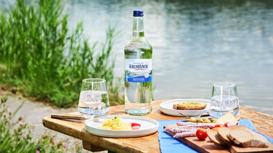 Picknicktisch mit Krumbach Medium Mineralwasser und Brotzeit am See in der Allgäuer Natur