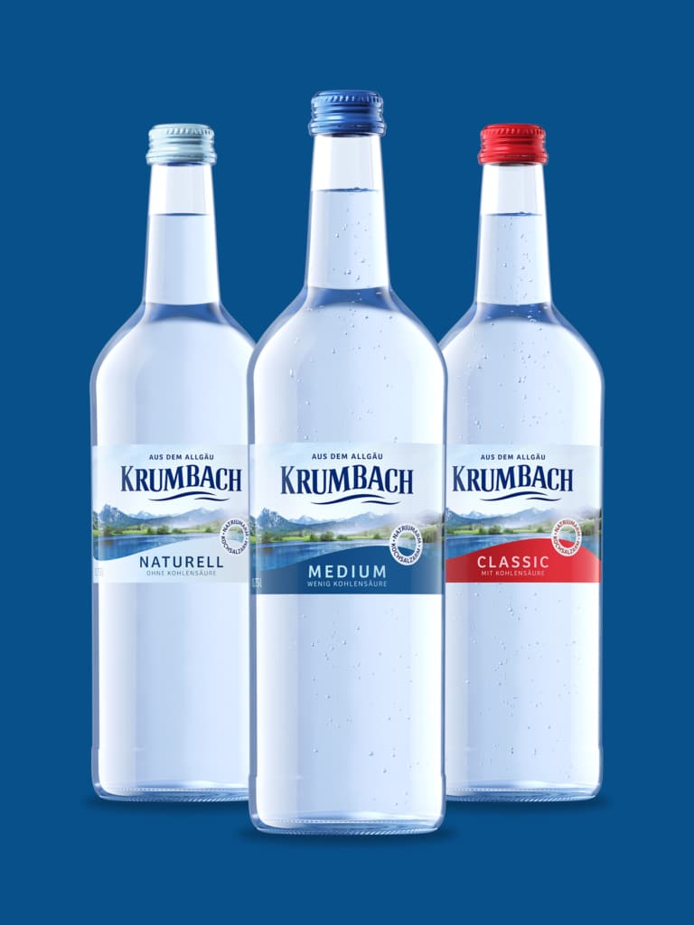 Krumbach Mineralwasser in den Sorten Naturell, Medium und Classic vor blauem Hintergrund