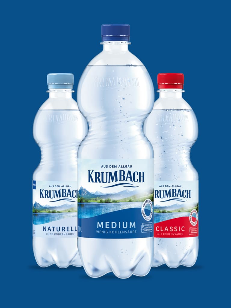 Krumbach Mineralwasser PET-Flaschen mit Naturell, Medium und Classic vor blauem Hintergrund